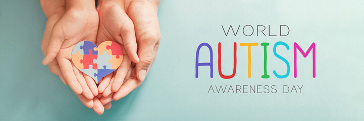 Adult and chiild hands holding jigsaw puzzle heart shape, Autism awareness, Autism spectrum family support concept, World Autism Awareness Day