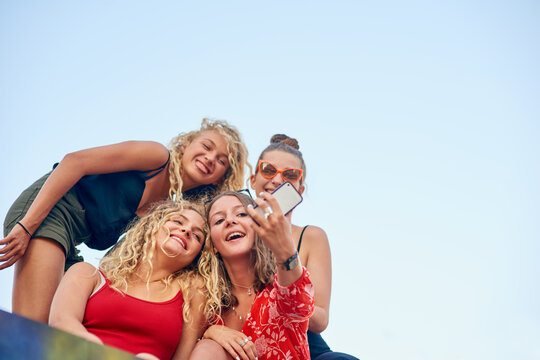 Its all about the angle. Low angle shot of a group of attractive young girlfriends taking selfies in the city.