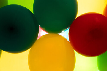 Colorful balloons all over the frame, lying one next to the other.  Many colored balloons looking like colored balls
