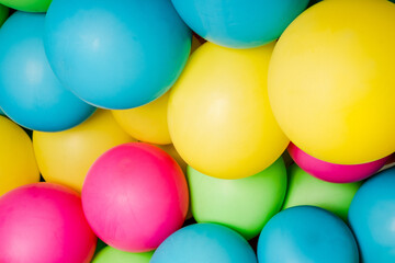 Colorful balloons all over the frame, lying one next to the other.  Many colored balloons looking like colored balls
