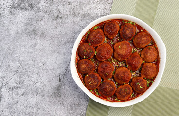 Homemade meatballs with tomato sauce in a white baking dish on a dark grey background. Top view, flat lay
