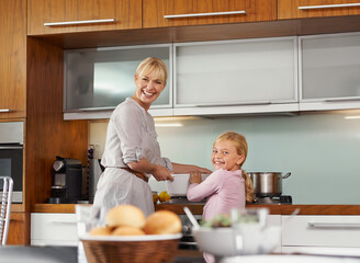 Fun times with mom in the kitchen. Portrait of an attractive young woman in the kitchen with her adorable daughter.