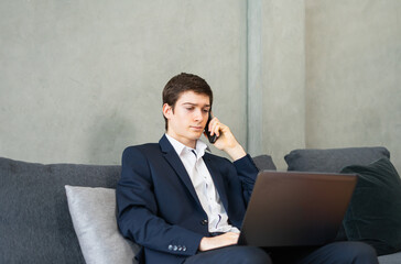 caucasian businessman work with computer, calling by mobile phone, wear suit, sitting, looking at laptop, copy space at background. Young man work business with home office background and copy space