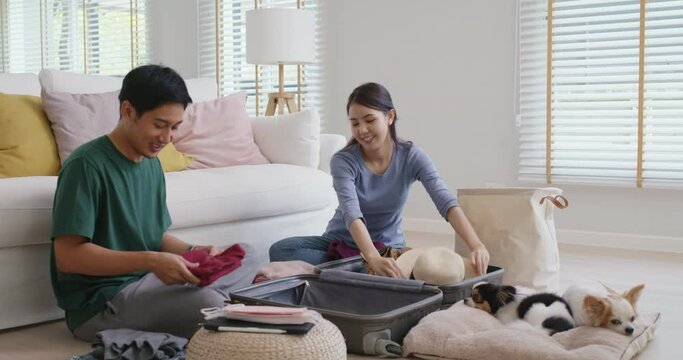 Relax safe pet lover family get away ready to get back to road trip. Asia people man woman choose clothing with love smile happy plan enjoy sit laugh fun folding stuff stack open and neat bag at home.