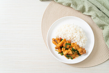 stir-fried fried fish with basil and chili in thai style topped on rice