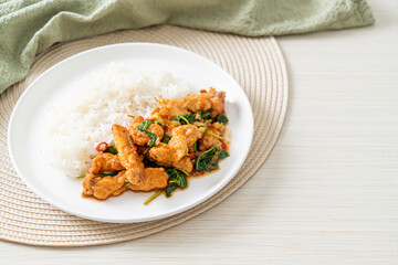 stir-fried fried fish with basil and chili in thai style topped on rice