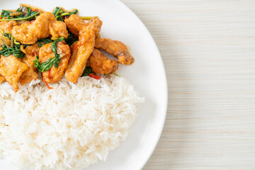 stir-fried fried fish with basil and chili in thai style topped on rice