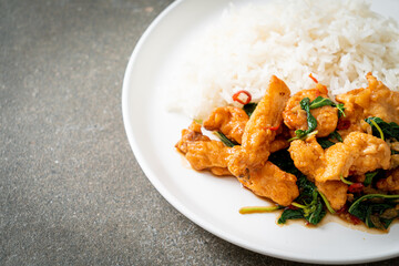 stir-fried fried fish with basil and chili in thai style topped on rice