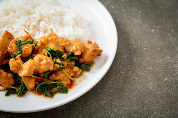 stir-fried fried fish with basil and chili in thai style topped on rice