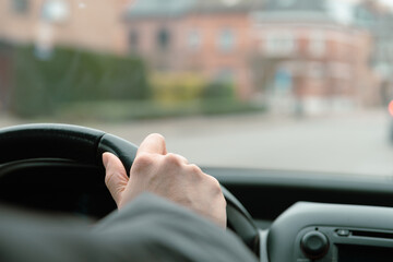 Hand of woman on a car steering wheel. Windshield and perspective of the road. Steering. Selected Focus.