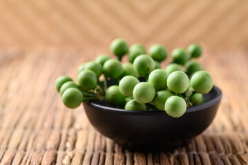Pea eggplant or Turkey berry (Solanum torvum) in bowl, Edible green fruits in Thai food curry or chili pastes