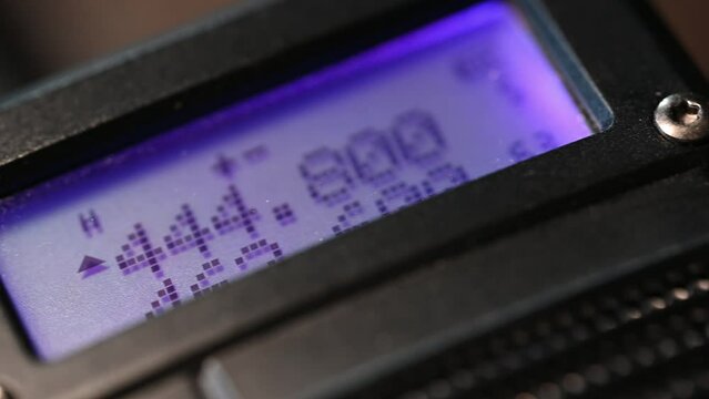 close-up of a handheld HAM radio.  Color lights up the screen on this slider shot
