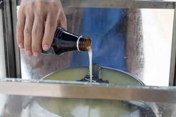 A man's hand is pouring oil into the lantern as it is a Buddhist belief that enhances good fortune.
