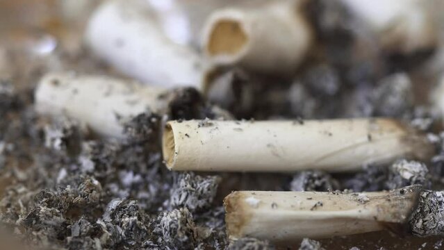 Extreme close up of cigarette butts in a full ash tray
