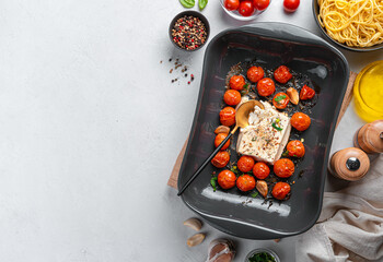 Oven-baked feta cheese pasta with cherry tomatoes, garlic and herbs on a gray background.
