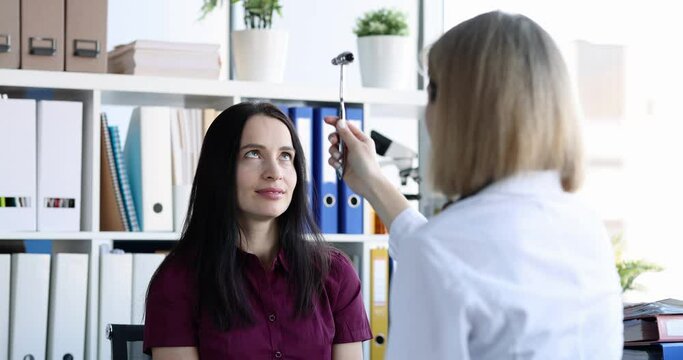 Neurologist checks reflexes with hammer while examining female patient