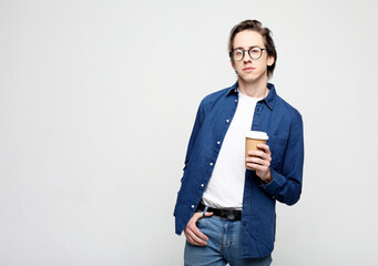 Young man standing with takeaway coffee, happy carefree handsome guy in eyewear