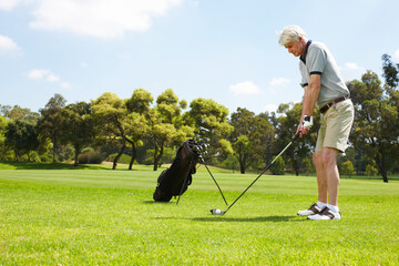 Getting his stance just right.... Senior man getting ready to swing on the golf course.