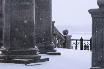 Balustrade of the rotunda under the snow. Gray granite exterior details during a snowfall. Fragment...