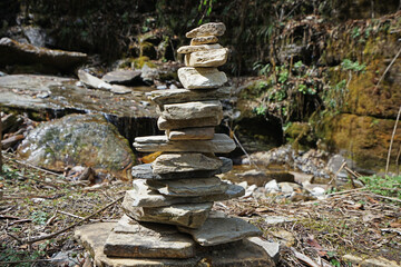 Prayer stone stacks among natural landscape of waterfall cascade and green forest park