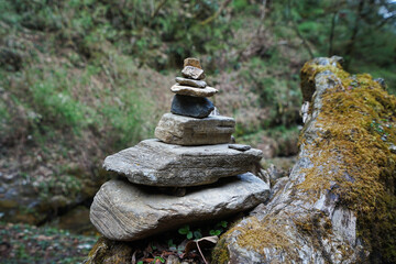 Prayer stone stacks among natural landscape of waterfall cascade and green forest park