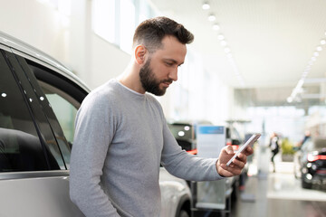 the buyer in the dealership auto center chooses a car compares prices in a smartphone via the Internet