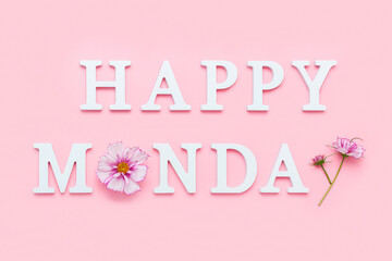 Happy Monday. Motivational quote from white letters and beauty natural flowers on pink background....