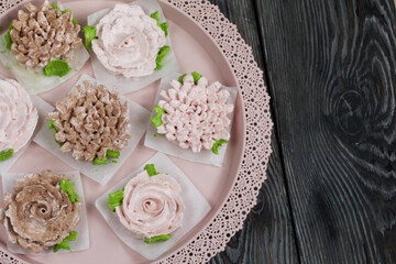 Homemade marshmallows of different shapes and colors. Zephyr flowers. On pine boards.