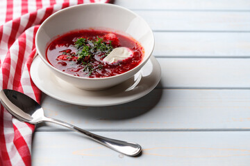 Bowl of beet root soup borsch on white wooden background