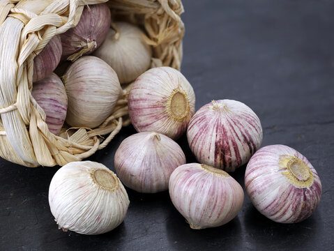 solo garlic or chinese garlic, Allium sativum in a straw basket on a black slate background