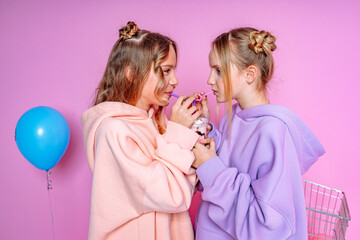 Two beautiful attractive funny joyful cheerful relaxed carefree girls dressed in casual fashion clothes isolated on hot pink background