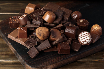 Chocolate pieces and candy on dark wooden table.