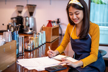 Fototapeta na wymiar Asian women Barista smiling and using coffee machine in coffee shop counter - Working woman small business owner food and drink cafe concept