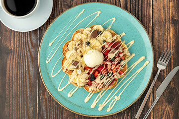 Heart waffle with banana and strawberry with gummy candy and ice cream on it