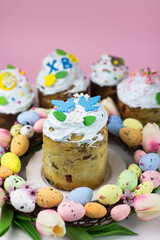 Fototapeta na wymiar Easter card. Kulich with sugar fudge in a wreath of tulips and eggs. Marshmallow fudge with decoration.