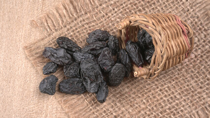 black raisins in a bowl on a wooden table. black raisins in a spoon