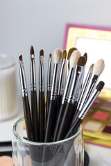 Makeup brushes against the background of shadows and sculptures. Make-up artist's desk