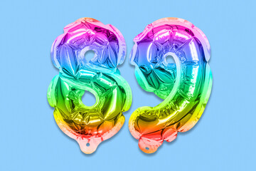 Rainbow foil balloon number, digit eighty nine on a blue background. Birthday greeting card with inscription 89. Top view. Numerical digit. Celebration event, template.