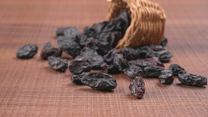 black raisins in a bowl on a wooden table. black raisins in a spoon