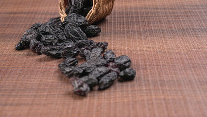 black raisins in a bowl on a wooden table. black raisins in a spoon