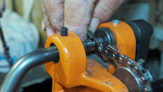 Man rivetes chain saw links with a special riveting machine. Close-up shot with selective focus