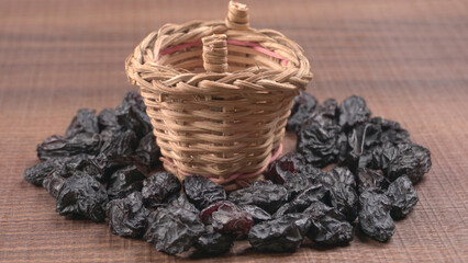 black raisins in a bowl on a wooden table. black raisins in a spoon