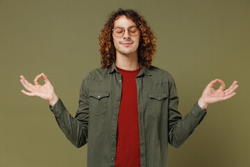 Spiritual tranquil young brunet curly man 20s wears khaki shirt hold spreading hands in yoga om aum...