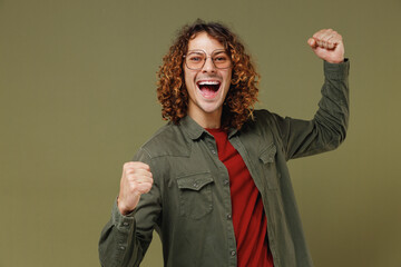 Excited fun young brunet curly man 20s wears khaki shirt jacket glasses doing winner gesture...