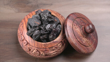 black raisins in a bowl on a wooden table. black raisins in a spoon