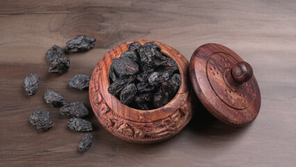 black raisins in a bowl on a wooden table. black raisins in a spoon