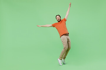 Fototapeta na wymiar Full body young man 20s wear casual orange t-shirt dancing stand on toes leaning back fooling around isolated on plain pastel light green color background studio portrait. People lifestyle concept