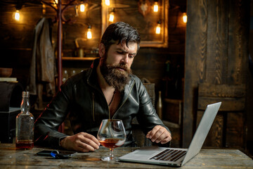 Bearded business man with glass of whiskey. Stressed from hard work.