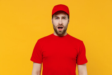 Fototapeta premium Professional displeased sad dissatisifed delivery guy employee man in red cap T-shirt uniform workwear work as dealer courier look camera isolated on plain yellow background studio. Service concept.