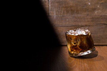 Ice coffee on a wooden table with cream being poured into it showing the texture and refreshing look of the drink